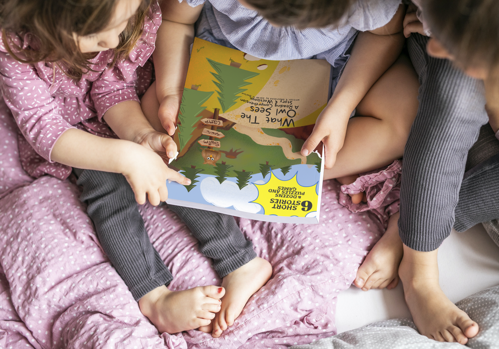 three children reading a children's book on a bed